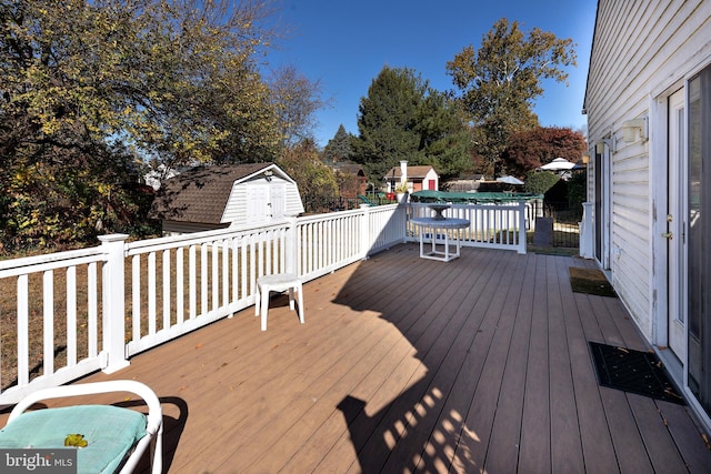 wooden terrace featuring a storage unit and a swimming pool