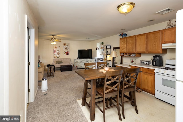 kitchen featuring light carpet, ceiling fan, and gas range gas stove