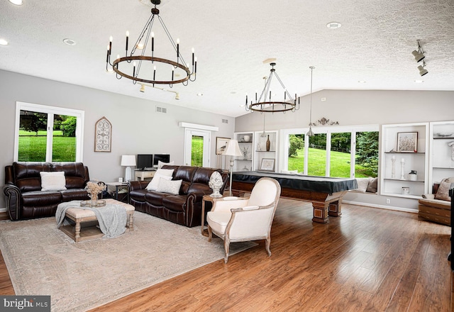 living room with a notable chandelier, plenty of natural light, lofted ceiling, and hardwood / wood-style flooring