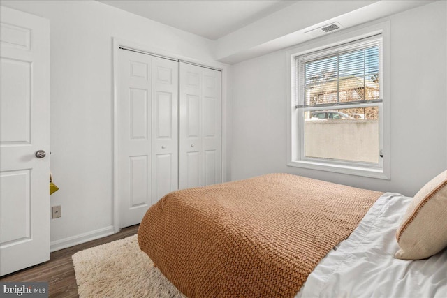 bedroom with dark wood-type flooring and a closet