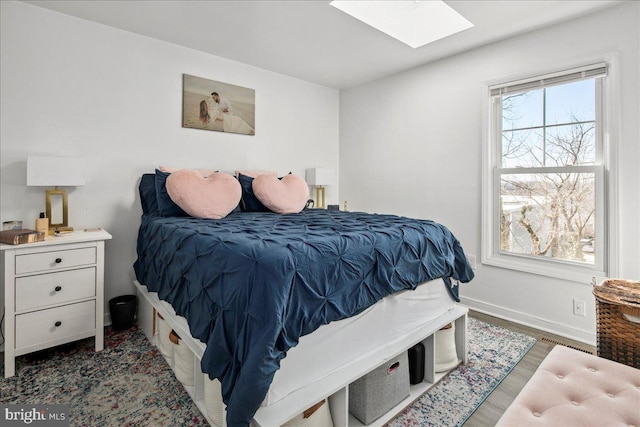 bedroom with dark hardwood / wood-style flooring and a skylight