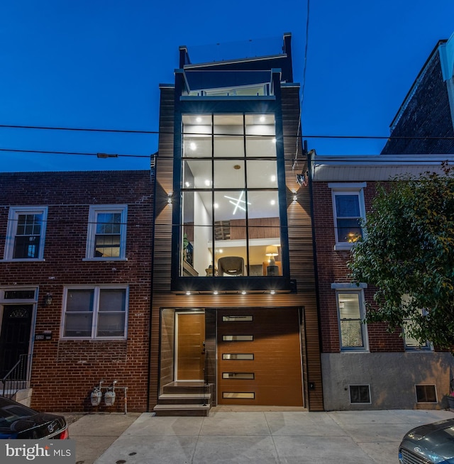 view of front facade featuring entry steps, brick siding, driveway, and an attached garage