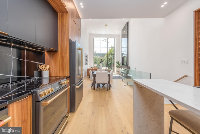 217 Tasker St, Philadelphia, PA 19148 - kitchen featuring stainless steel appliances, decorative backsplash, light wood finished floors, brown cabinetry, and modern cabinets
