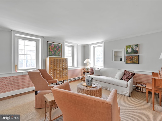 carpeted living area featuring a baseboard heating unit, baseboards, and crown molding