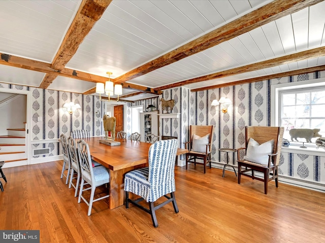 dining room featuring beam ceiling, wood finished floors, stairs, and wallpapered walls