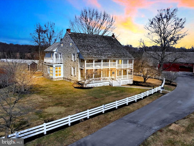 view of front of property featuring a fenced front yard, a yard, a porch, and a balcony