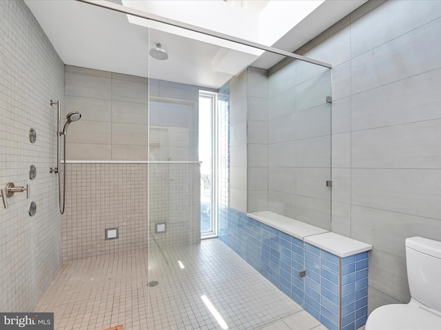 bathroom featuring tile walls, toilet, and a stall shower