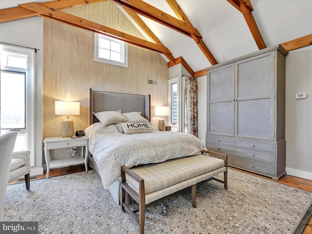 bedroom with visible vents, baseboards, wood finished floors, and vaulted ceiling with beams