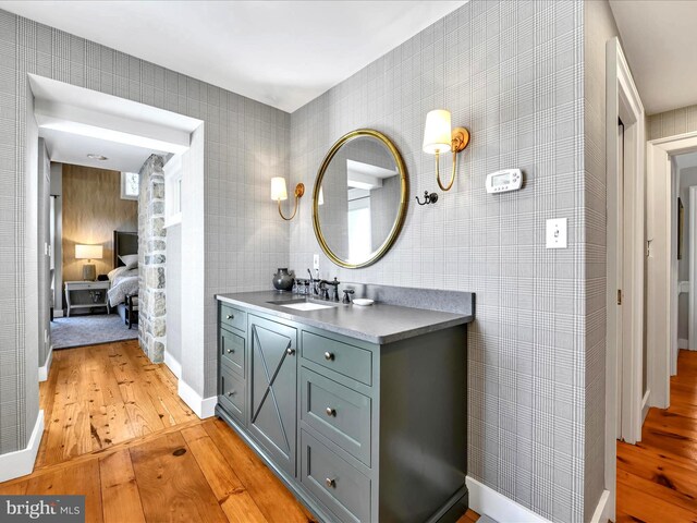 ensuite bathroom with connected bathroom, baseboards, vanity, and hardwood / wood-style flooring