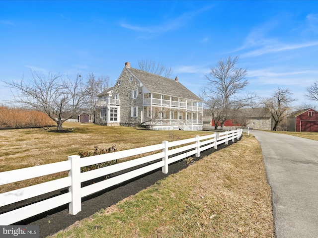 view of front of house with a fenced front yard, a balcony, and a front lawn