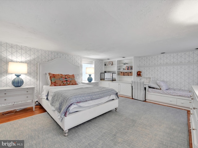 bedroom featuring light wood-type flooring, a textured ceiling, and wallpapered walls