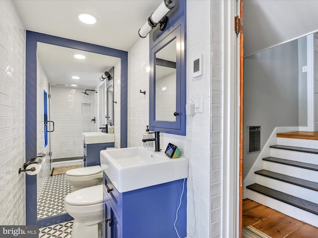 bathroom featuring toilet, recessed lighting, tile walls, a shower stall, and vanity