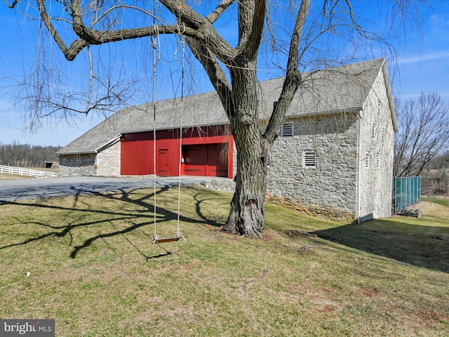 exterior space with stone siding, an outbuilding, a barn, and a front yard