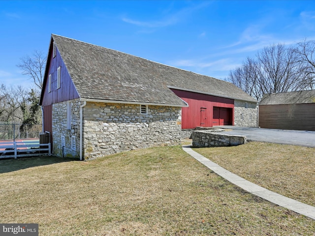 exterior space with an outdoor structure, a lawn, and stone siding