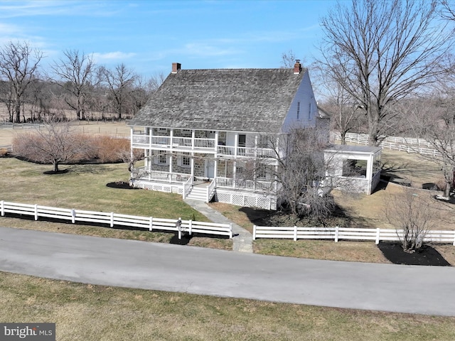 view of front of house featuring a fenced front yard, covered porch, a front yard, and a balcony