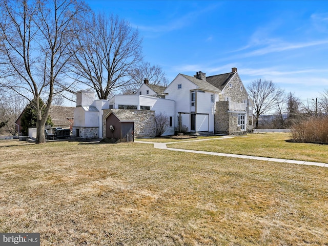 view of property exterior featuring stone siding, a lawn, an attached garage, and a chimney