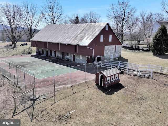 exterior space featuring stone siding, metal roof, and fence