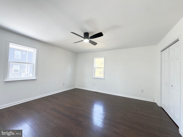 unfurnished bedroom featuring a closet, dark wood-style flooring, ceiling fan, and baseboards