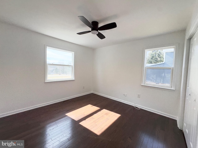 unfurnished room with dark wood-style floors, plenty of natural light, and baseboards