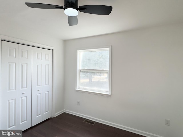 unfurnished bedroom featuring baseboards, visible vents, a ceiling fan, dark wood-style flooring, and a closet