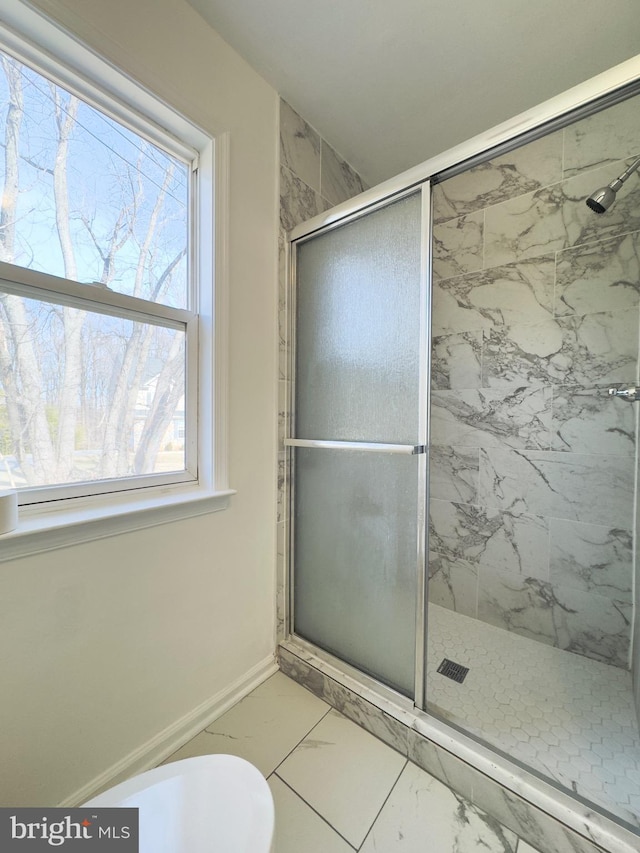 bathroom featuring toilet, marble finish floor, baseboards, and a stall shower