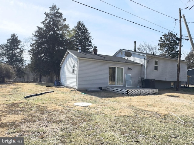 back of house featuring a deck, a yard, a chimney, and central air condition unit