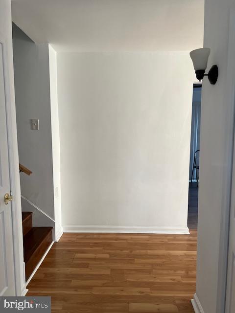 spare room featuring stairs, baseboards, and wood finished floors