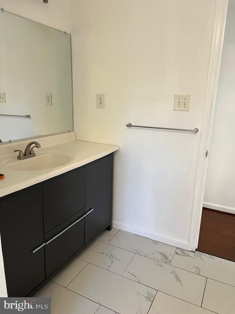 bathroom featuring marble finish floor, vanity, and baseboards