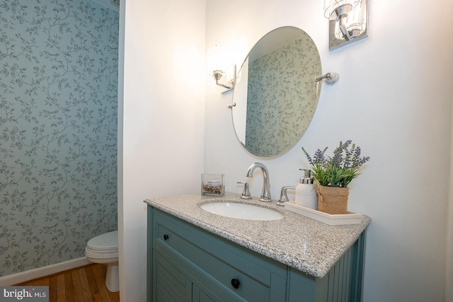 bathroom with vanity, wood finished floors, toilet, and baseboards