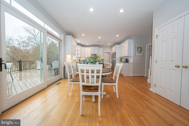 dining space with light wood-type flooring, visible vents, and recessed lighting