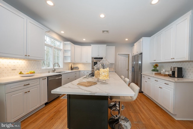 kitchen featuring a center island, visible vents, appliances with stainless steel finishes, white cabinetry, and a kitchen bar