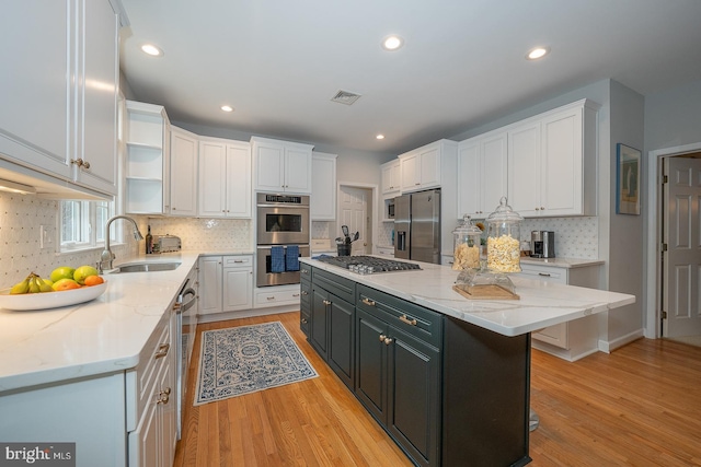 kitchen with stainless steel appliances, white cabinetry, a sink, and open shelves