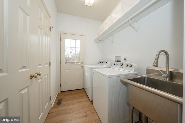 washroom with laundry area, visible vents, light wood-style floors, separate washer and dryer, and a sink