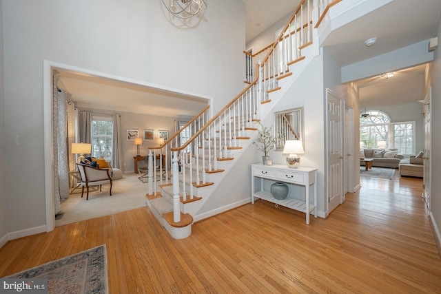 staircase with hardwood / wood-style flooring, plenty of natural light, a high ceiling, and baseboards