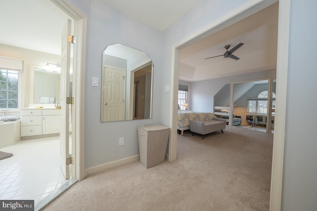 bedroom with ensuite bath, multiple windows, baseboards, and light colored carpet