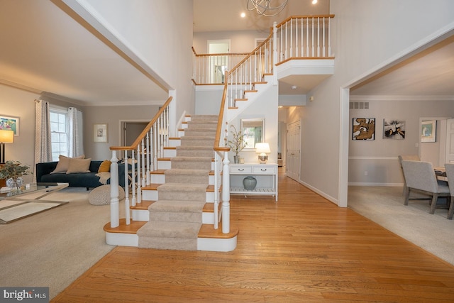 stairway with carpet floors, ornamental molding, and a towering ceiling