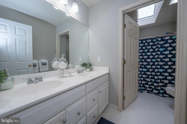 full bathroom with a skylight, tile patterned floors, a sink, and double vanity