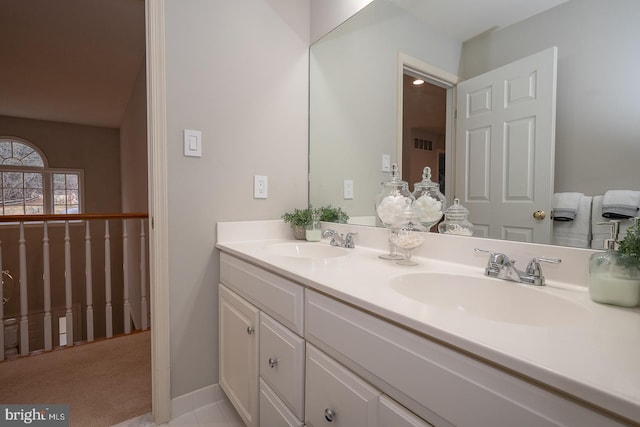 bathroom with double vanity, baseboards, visible vents, and a sink