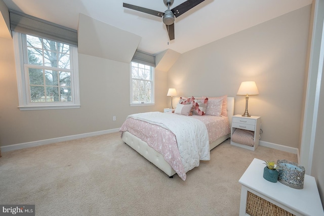 bedroom featuring light carpet, vaulted ceiling, baseboards, and ceiling fan