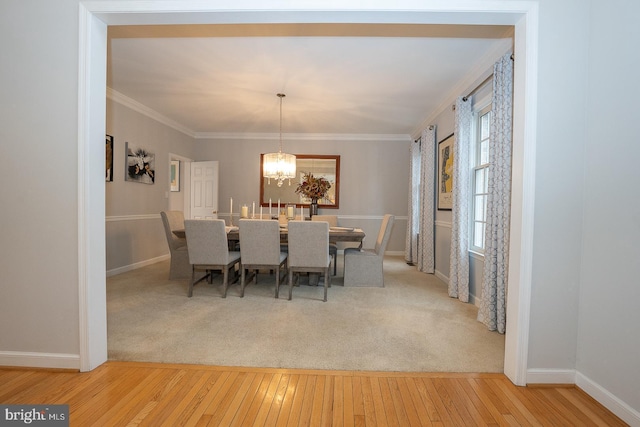 dining room with ornamental molding, light wood-type flooring, an inviting chandelier, and baseboards