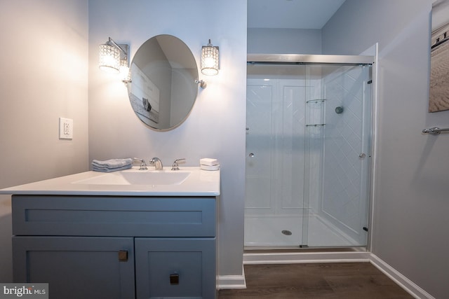 bathroom with a stall shower, baseboards, wood finished floors, and vanity