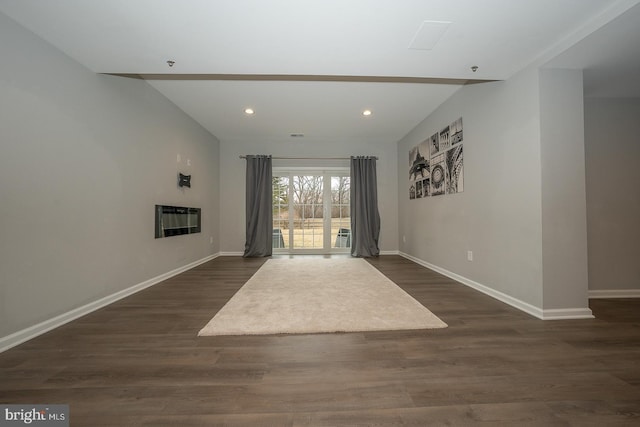 unfurnished living room featuring baseboards, a glass covered fireplace, dark wood-type flooring, and recessed lighting