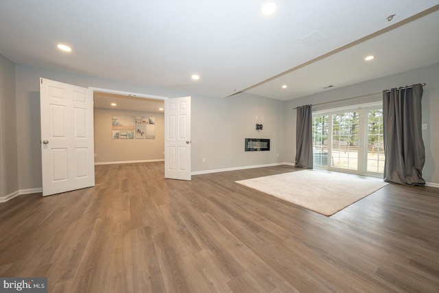 unfurnished living room featuring recessed lighting, wood finished floors, and baseboards