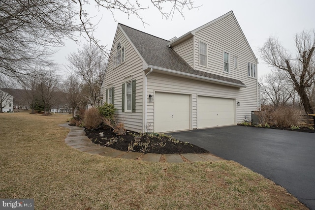 view of home's exterior with driveway, a lawn, and roof with shingles