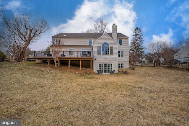 rear view of property featuring a chimney, a lawn, a deck, and fence