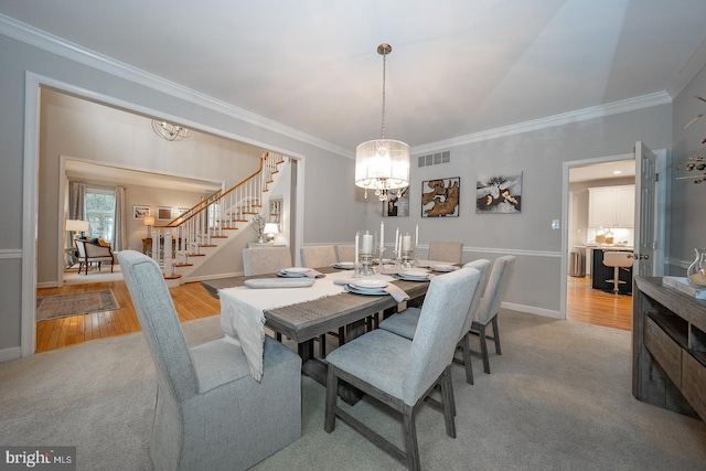 carpeted dining area featuring stairs, wood finished floors, visible vents, and crown molding