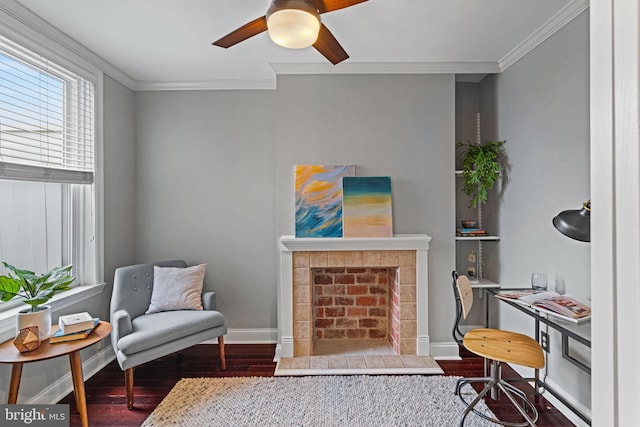 sitting room with baseboards, a fireplace, wood finished floors, and crown molding