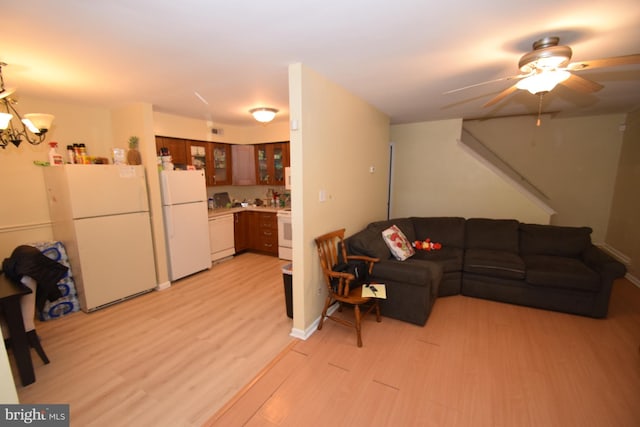 living room with ceiling fan with notable chandelier and light wood-type flooring