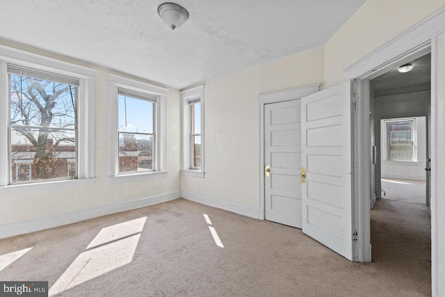 interior space with baseboards, a textured ceiling, and light colored carpet