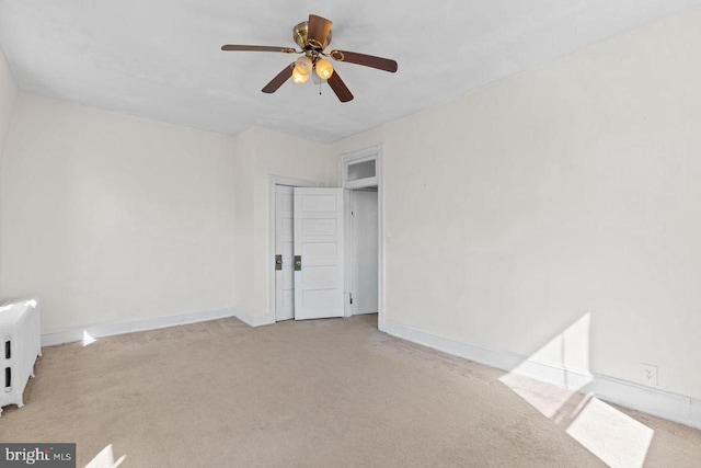 unfurnished room with a ceiling fan, light carpet, and baseboards